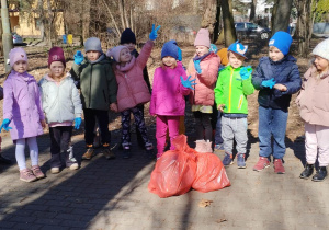 Dzieci z grupy Pszczółek prezentują zebrane śmieci w workach