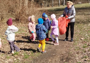 Dzieci wraz z Panią podczas zbierania śmieci w parku