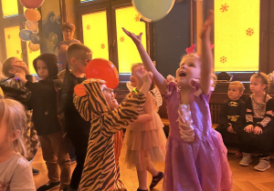 Na zdjęciu dzieci podrzucają balonami podczas balu karnawałowego.