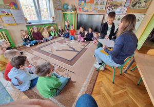 Na zdjęciu dziecko losuje od Pani kartę spośród kart o różnych sytuacjach związanymi z obcymi osobami.
