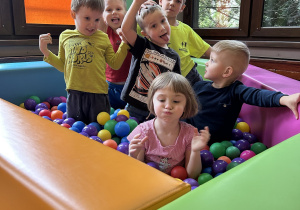 Na zdjęciu grupa chłopców w basenie z kolorowymi kulkami.