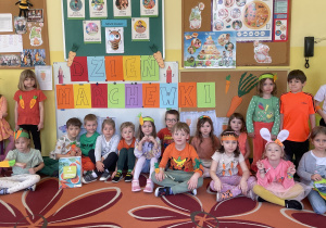 Dzieci z grupy pszczółek pozują na tle napisu "Dzień Marchewki"