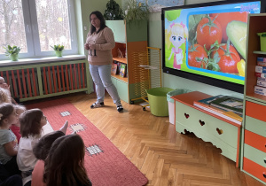 Nauczycielka omawiająca prezentowane warzywa na tablicy multimedialnej