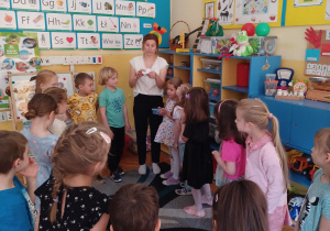 dzieci i nauczycielka stojące w kole podczas zabawy edukacyjnej