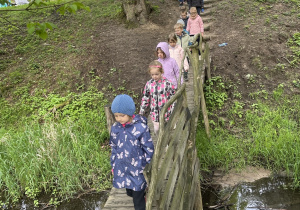 dzieci przechodzące przez drewniany mostek