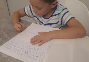 Antoś ćwiczy rysowanie szlaczków literopodobnych i pisanie liter w liniaturze.