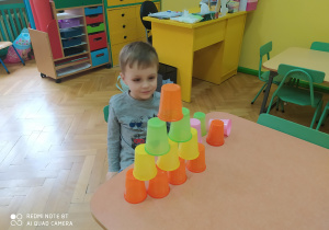 Chłopiec podczas układania kolorowych kubków wg podanego wzoru