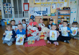 zdjęcie przedstawia uśmiechnięte dzieci prezentujące swoje prace