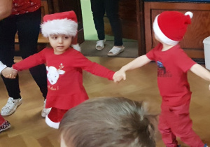 dzieci tańczą w czerwonych strojach i czapkach mikołajkowych