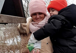 Zdjęcie przedstawia chłopca wsypującego ziarenka do karmnika.