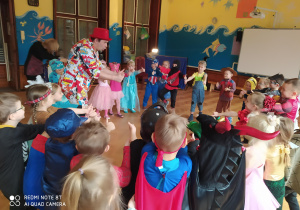 zdjęcie przedstawia przedszkolaki w strojach karnawałowych podczas zabawy z wodzirejem