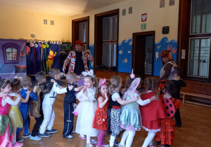 Zdjęcie przedstawia przedszkolaki w strojach karnawałowych podczas zabawy z wodzirejem i nauczycielką.