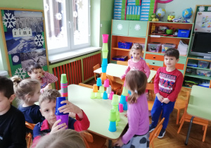 Zdjęcie przedstawia budowle wykonane z kubeczków przez dzieci oraz autorów tych budowli.