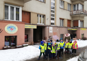 Na zdjęciu grupa dzieci stojąca na ulicy przed wejściem do teatru "Baśniowa Kawiarenka".