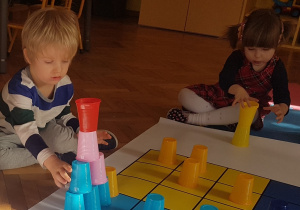 dzieci budują wieże z kolorowych kubeczków.