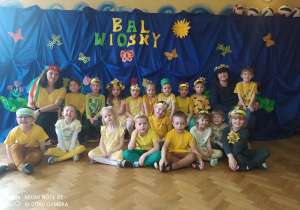 Dzieci z grupy czwartej wraz z nauczycielkami pozują do zdjęcia grupowego na tle napisu "Bal wiosny"