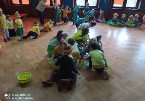 Przedszkolaki podczas konkursu, zbierają kolorowe kwiaty do misek