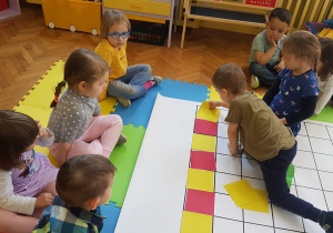 Dzieci układają rytm z kolorowych kartoników na macie do kodowania