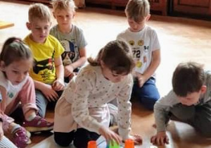Dzieci układają z kolorowych kubeczków na macie do kodowania sudoku.