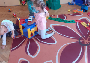 Na zdjęciu dzieci bawiące się plastikowymi torami.