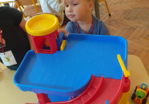 Na zdjęciu dzieci bawiące się plastikowymi torami.