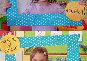 Na zdjęciu dwoje dzieci pozujących w niebieskiej ramce w kropki z napisem :Wierzę w siebie.. i kropka!"