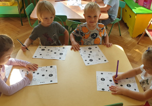 Na zdjęciu dzieci siedzące przy stoliku, wykonujące kartę pracy.