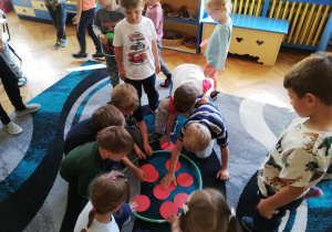 dzieci układają czerwone kółka origami w obręczy leżącej na dywanie