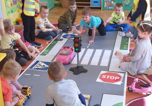 Zdjęcie przedstawia dzieci poruszające się po makiecie ulicy i pasów.