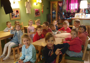 Dzieci siedzące przy stolikach oczekujące na rozpoczęcie spektaklu.