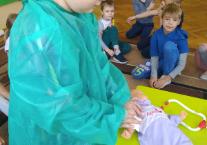 Dziewczynka podczas zajęć wykonuje badanie na lalce