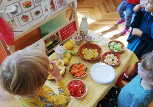 dzieci nakładają sobie po kolei na swoje talerzyki ekologiczne przysmaki z tzw. "szwedzkiego stołu"