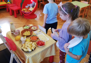 dzieci nakładają sobie po kolei na swoje talerzyki ekologiczne przysmaki z tzw. "szwedzkiego stołu"