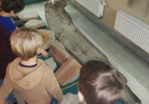 grupa dzieci przygląda się eksponatowi - jest to fragment żuchwy ogromne ryby