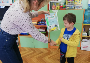 nauczycielka wręcza chłopcu dyplom i nagrodę za udział w konkursie