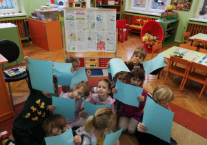 Dzieci oglądają poszczególne kartki książeczki Konwencja o Prawach Dziecka