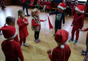dzieci stoją w kole podczas zabawy "kto zostanie z czapką w ręce , gdy umilknie muzyka"