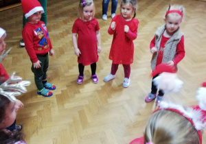 dzieci stoją w kole podczas zabawy "kto zostanie z czapką w ręce , gdy umilknie muzyka"
