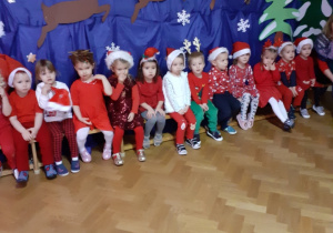 Zdjęcie przedstawia dzieci siedzące na ławeczce