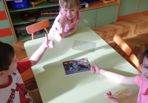 Dzieci przy stolikach w małych zespołach układają puzzle na czas​