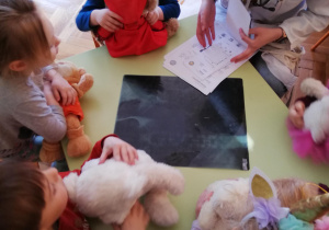 dzieci przy stolikach wraz ze studentką podczas zabaw oswajających dzieci z pracą lekarza i pielęgniarki