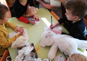 dzieci przy stolikach wraz ze studentką podczas zabaw oswajających dzieci z pracą lekarza i pielęgniarki