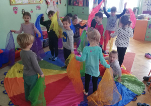 dzieci podczas zabaw muzyczno-ruchowych z wykorzystaniem kolorowych apaszek i chusty animacyjnej