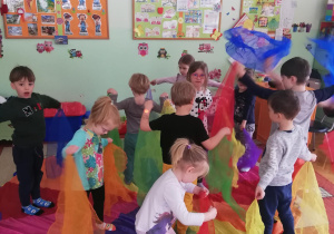 dzieci podczas zabaw muzyczno-ruchowych z wykorzystaniem kolorowych apaszek i chusty animacyjnej