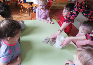 dzieci wypełniają ziemią i wsypują nasionka koperku