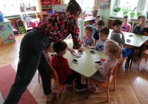 dzieci wypełniają ziemią i wsypują nasionka koperku