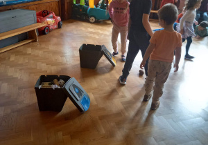Na zdjęciu dzieci segregują do koszy plastik i papier.