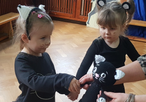 Dwie dziewczynki przebrane za kotki witają się z maskotką - „Kotkiem Psotkiem”