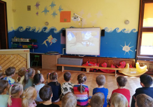 dzieci z gr. IV i VI oglądają film o tematyce patriotycznej na tablicy multimedialnej