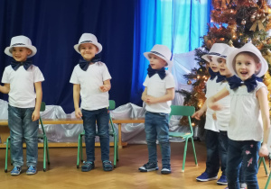 Dzieci z grupy Trzeciej podczas uroczystości ubrane w biało granatowe stroje.